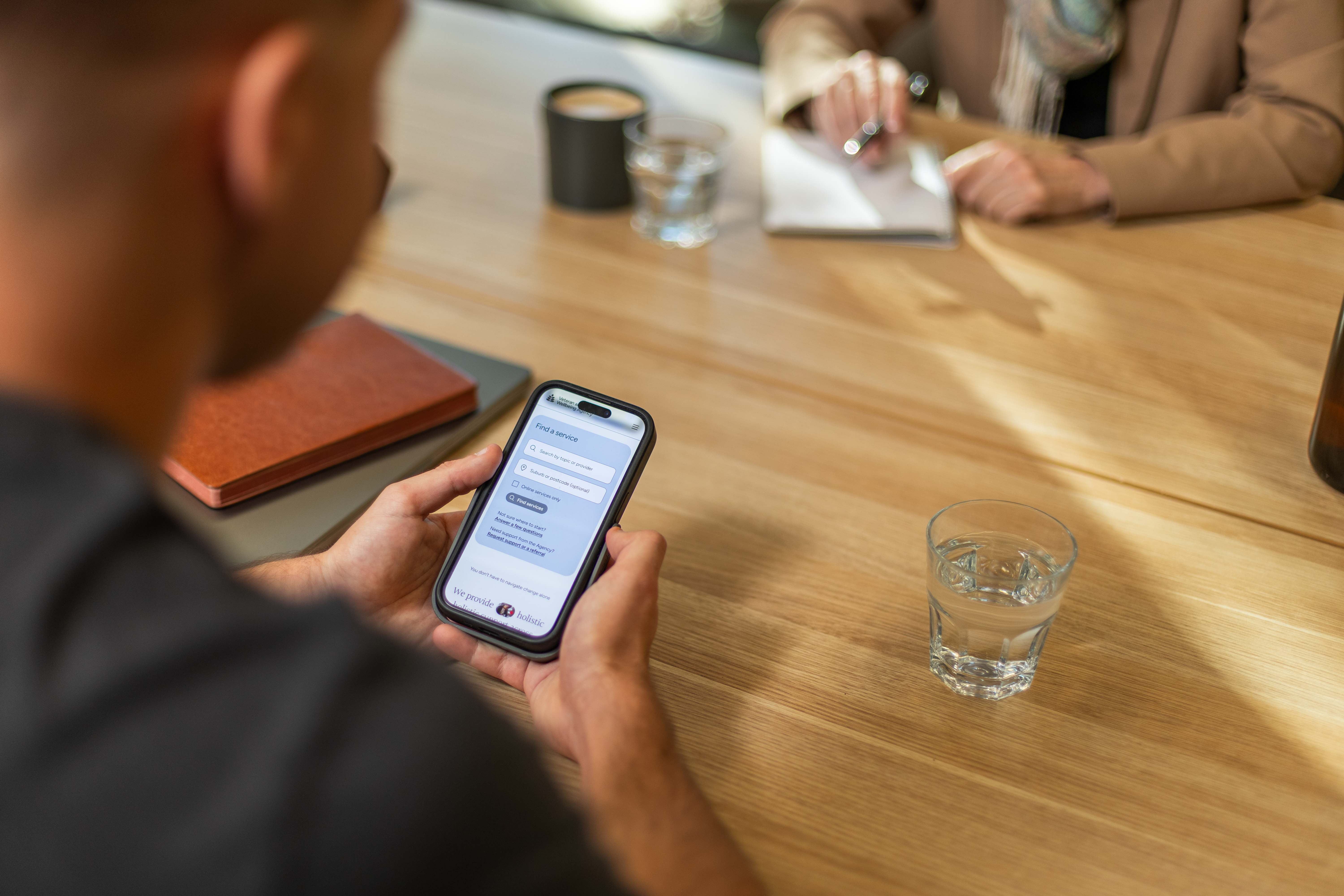 A person using a mobile phone to view the agency’s website in a community setting.