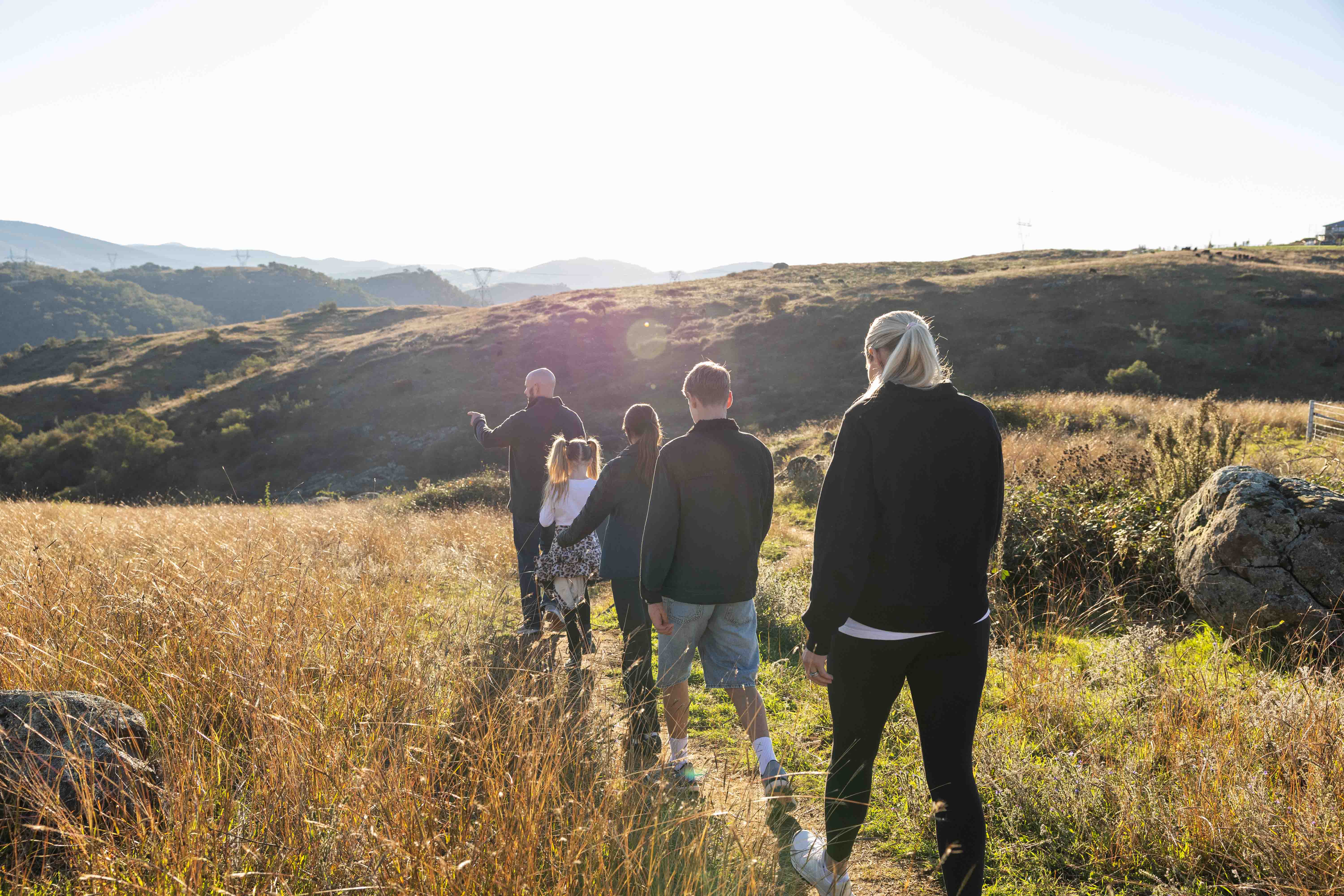 A family walking together along a path through a grassy hillside landscape. 