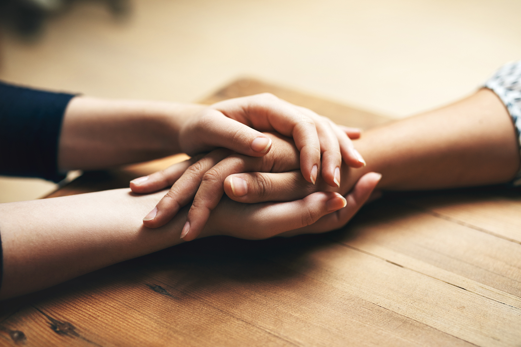 Close-up of two people holding hands across a table.