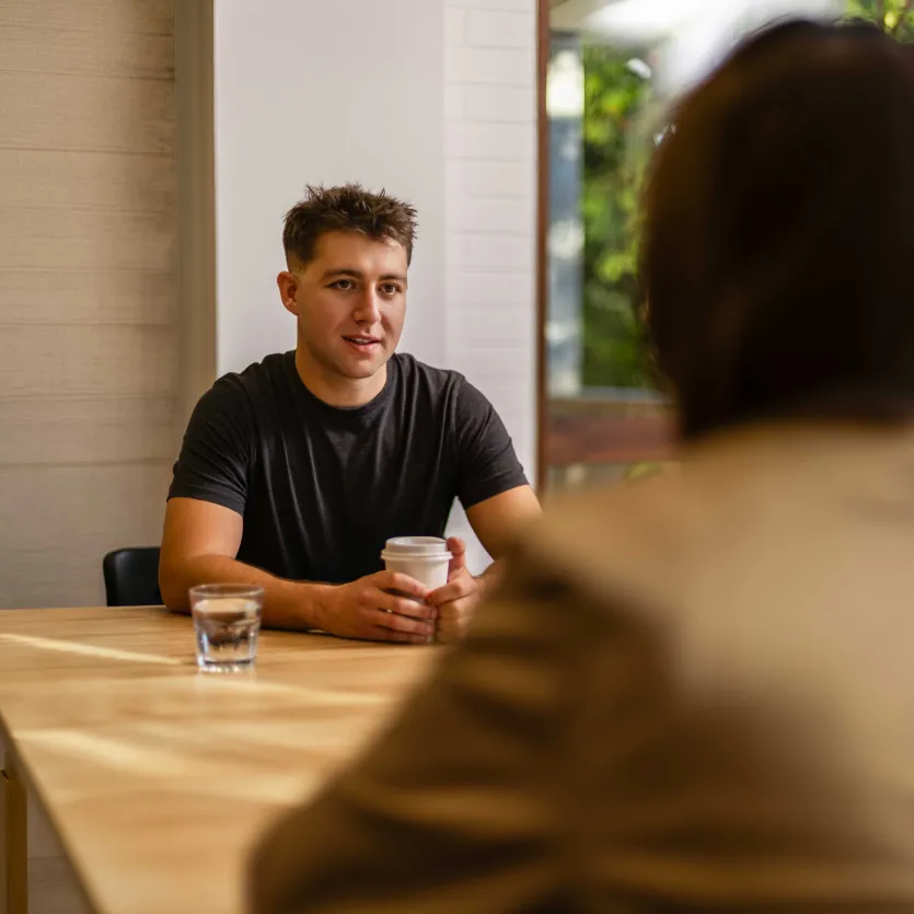 A person catching up over coffee with another person in a relaxed community setting.