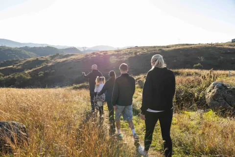 A family walking together along a path through a grassy hillside landscape. 