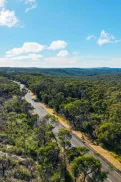 Aerial view of a road winding through bushland.