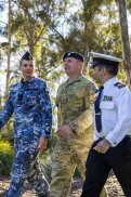 Three people in different Australian Defence Force uniforms walking side by side in a park.