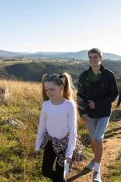 A family hiking together along a narrow path on a grassy hillside.