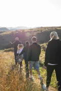 A family walking together along a path through a grassy hillside landscape. 