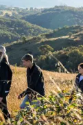 An adult and two teengage children walking together through a grassy hillside landscape, with the adult pointing into the distance.