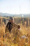 A person sitting in tall grass on a hillside, looking out over the landscape.