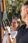 Two people using outdoor exercise equipment in a park setting.