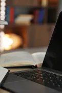 Open books stacked beside a laptop on a desk, with pages spread in a study setting.
