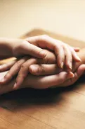 Close-up of two people holding hands across a table.