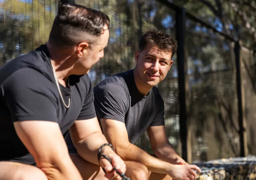 Two people sitting side by side, talking to each other in a park setting.
