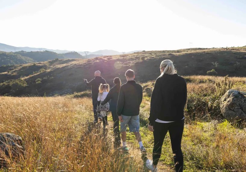 A family walking together along a path through a grassy hillside landscape. 