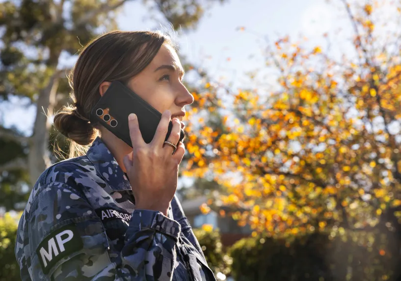 Close-up of a person in an Australian Defence Force uniform talking on a mobile phone outdoors.