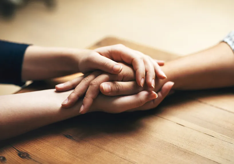 Close-up of two people holding hands across a table.